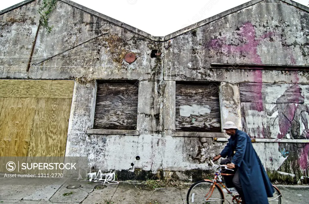 A bicyclist passes by an abandoned and blighted industrial building on St. Caluade Avenue, in the St. Roch neighborhood of New Orleans.