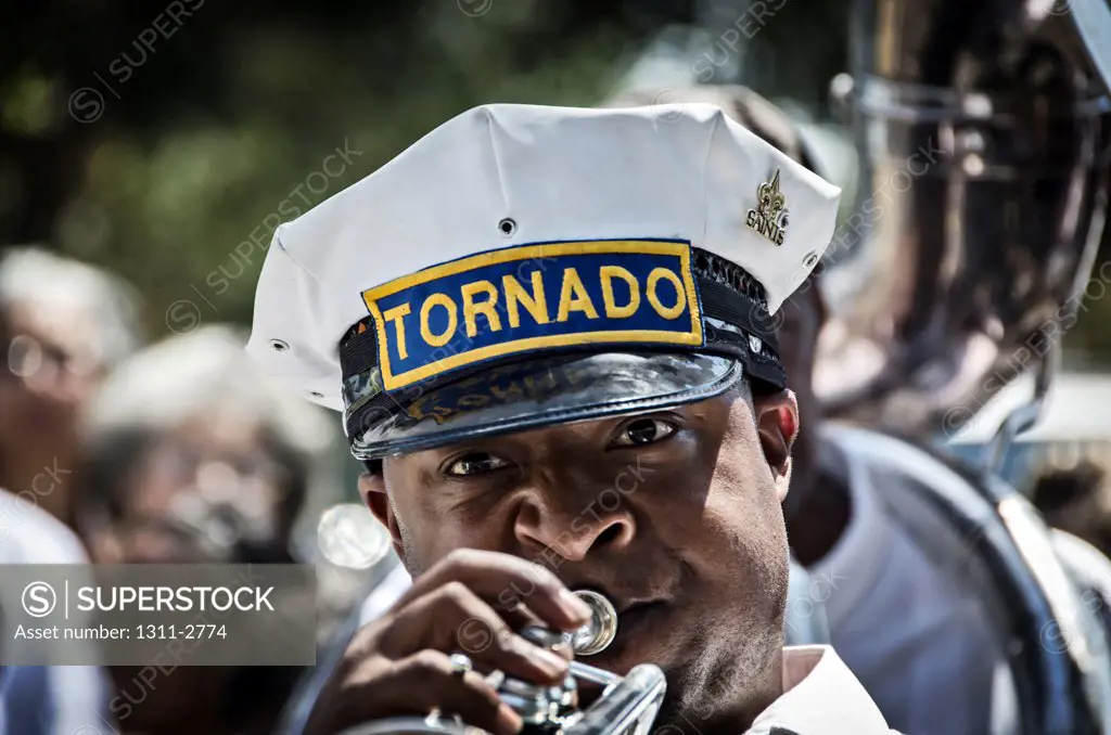 A trumpet player toots away as he walks with a marching band in a secondline parade.