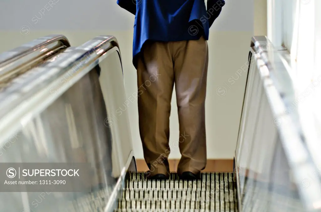 Businessman riding an escalator.