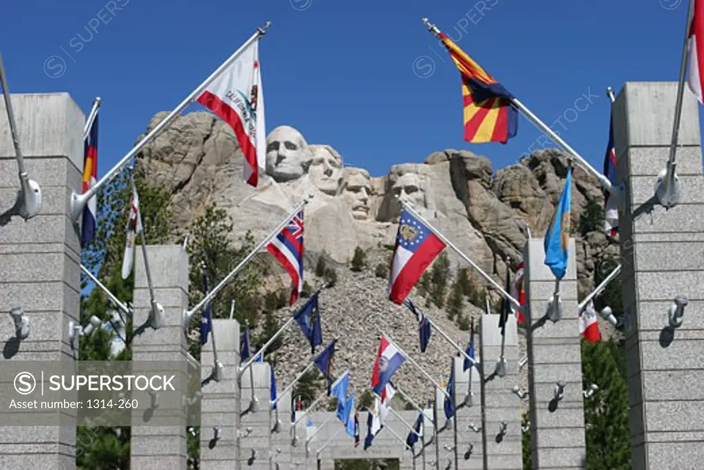 Flags on columns with the sculptures of former US presidents in the background, Mt Rushmore National Monument, Black Hills, South Dakota, USA