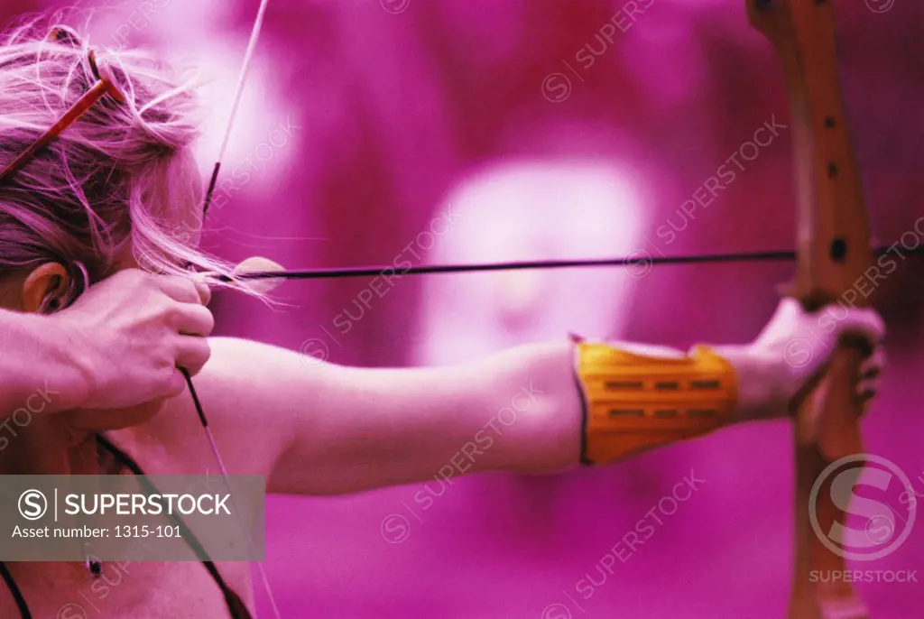 Close-up of a woman aiming with a bow and arrow