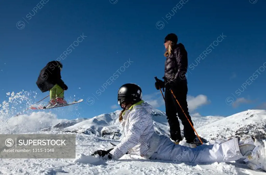 Teenage boys skiing with his mother and sister watching at him