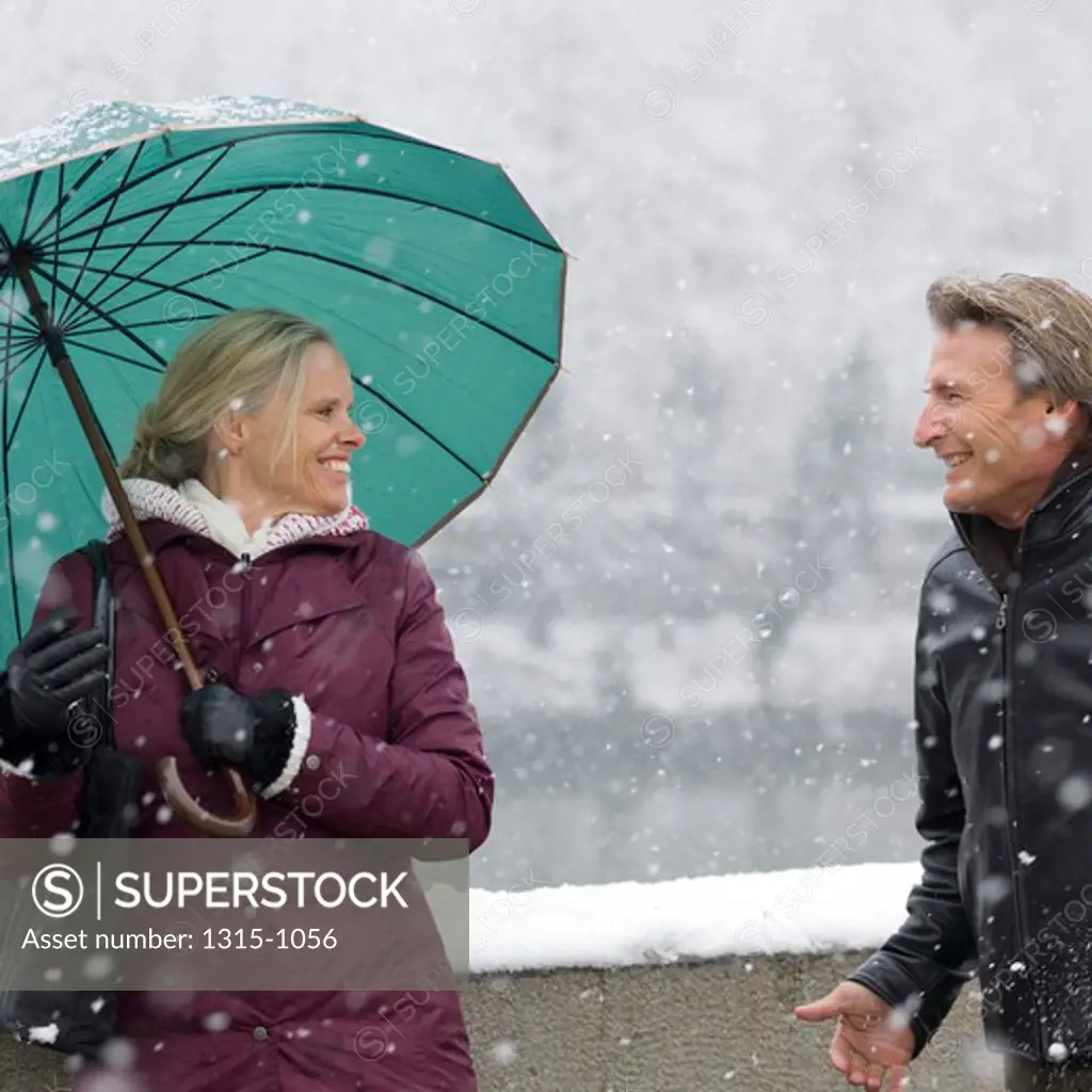 Couple walking in snowstorm with umbrella