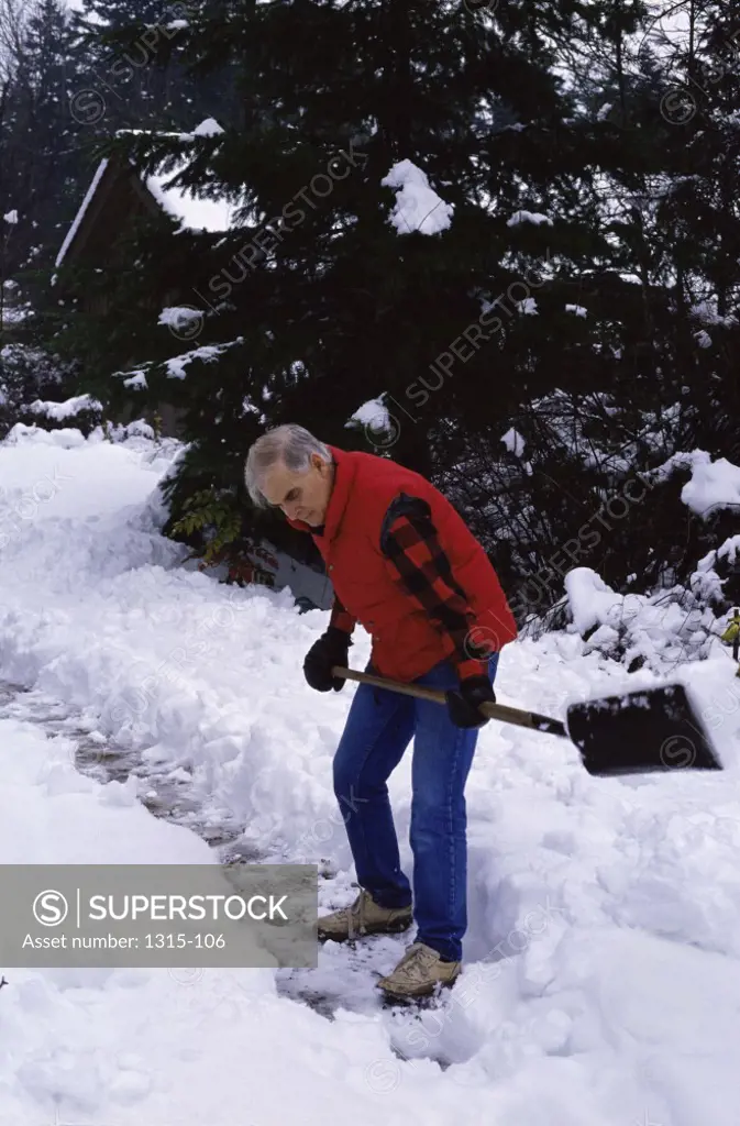 Side profile of a senior man shoveling snow