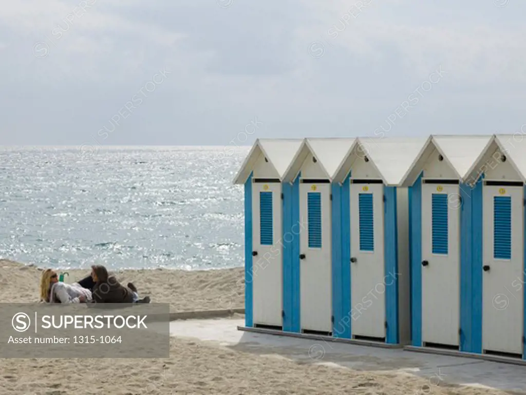 Couple lying on the beach near changing cubicles