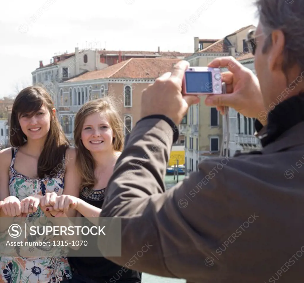 Mature man taking a photograph of his daughters, Grand Canal, Venice, Venice Province, Veneto, Italy