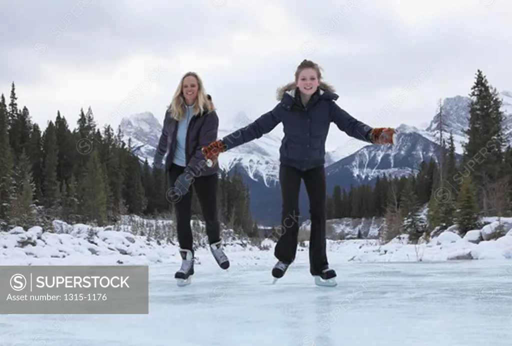 Woman skating with her daughter on a frozen creek, Alberta, Canada
