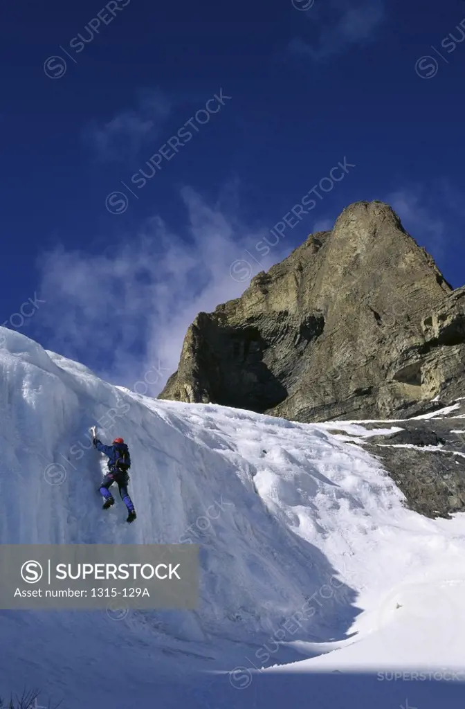 Low angle view of a man climbing an ice covered cliff, Banff National Park, Alberta, Canada