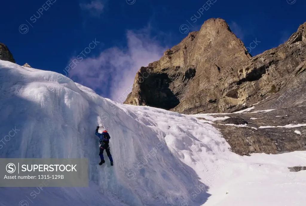 Low angle view of a man climbing an ice covered cliff, Banff National Park, Alberta, Canada