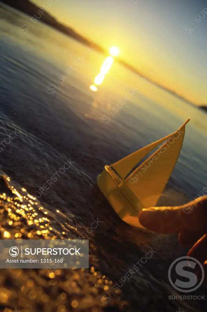 Person's hand placing a toy boat in water, Baja California, Mexico