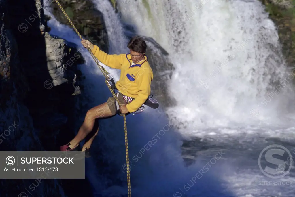 Mid adult man rappelling down from a cliff, Alberta, Canada