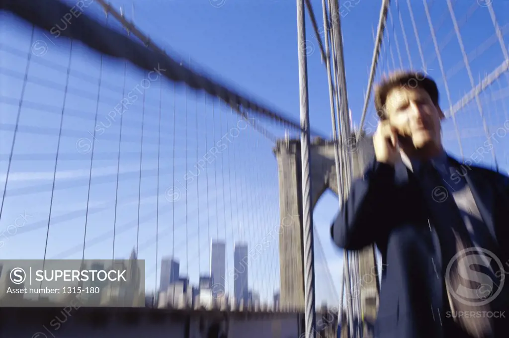 Low angle view of a businessman talking on a mobile phone, Brooklyn Bridge, New York City, New York, USA