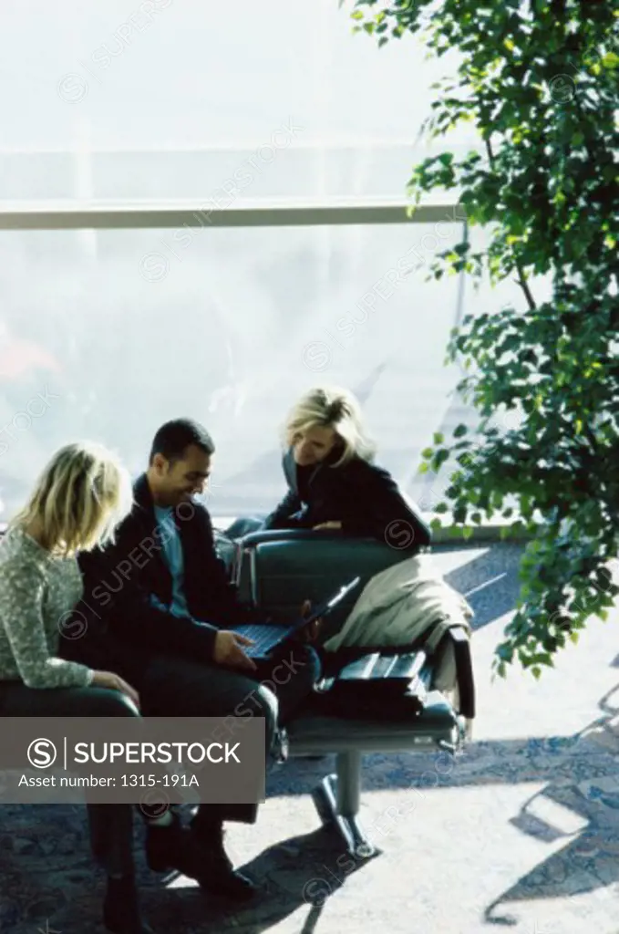 High angle view of a businessman and two businesswomen looking at a laptop