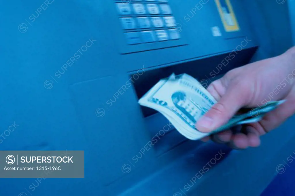 Close-up of a person's hand withdrawing cash from an ATM