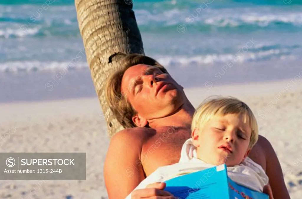 High angle view of a father and son sleeping on the beach