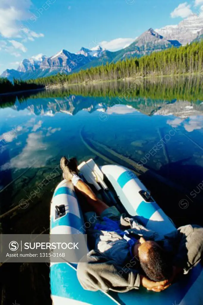 High angle view of a young man resting in an inflatable raft, Herbert Lake, Banff National Park, Alberta, Canada