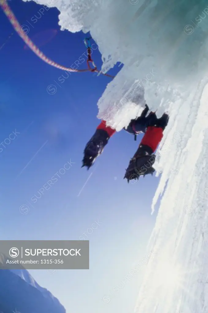 Low angle view of a person climbing an ice covered cliff