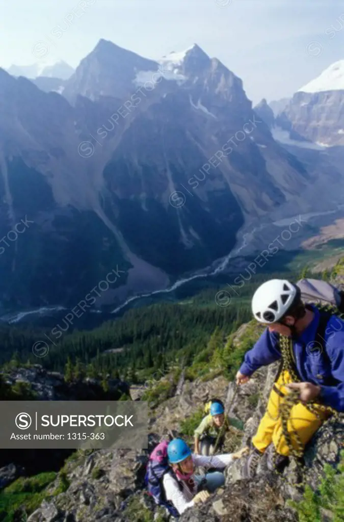 Two young women and a young man climbing a mountain, Lake Louise, Alberta, Canada