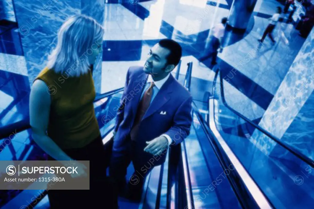 High angle view of a businessman and a businesswoman talking to each other on an escalator