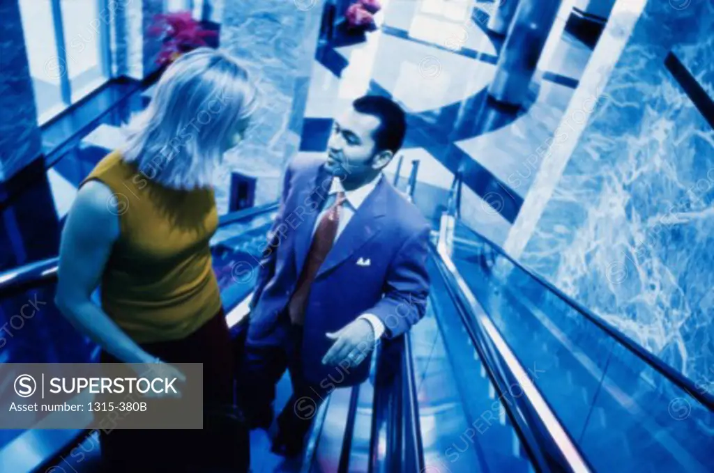 High angle view of a businessman and a businesswoman talking to each other on an escalator