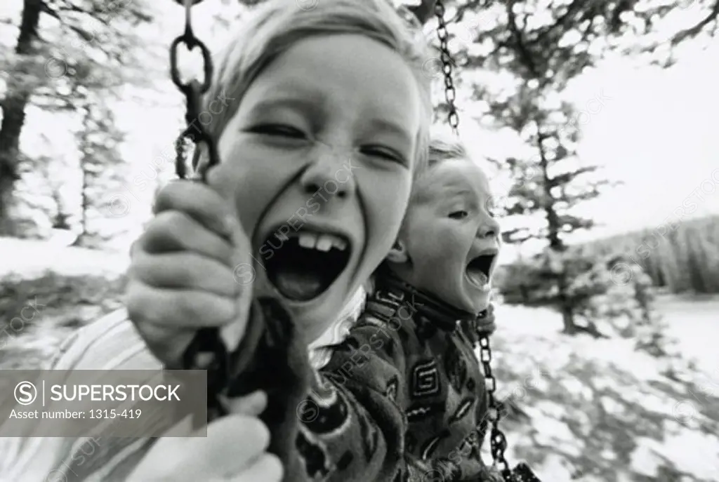 Close-up of two brothers swinging on a swing