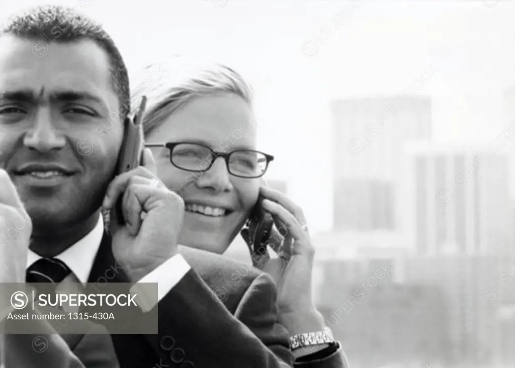 Close-up of a businessman and a businesswoman talking on a mobile phone
