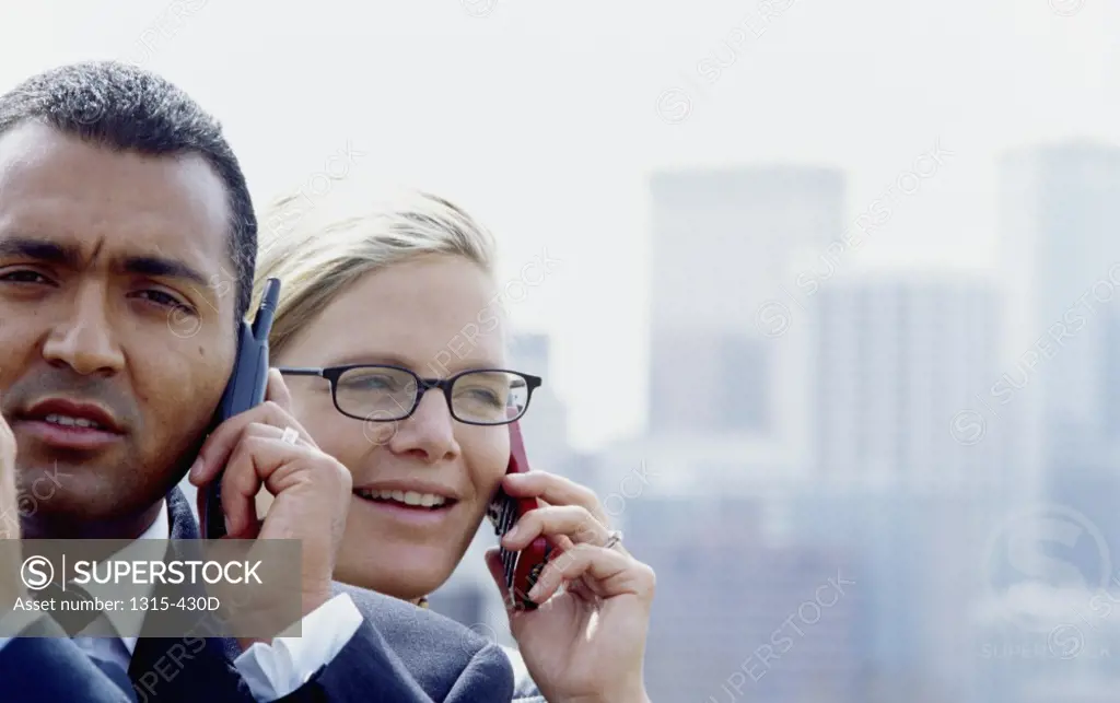 Close-up of a businessman and a businesswoman talking on a mobile phone
