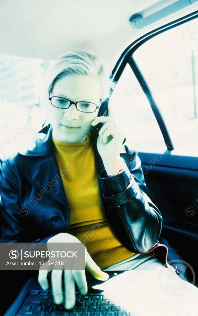 Businesswoman talking on a mobile phone in a car