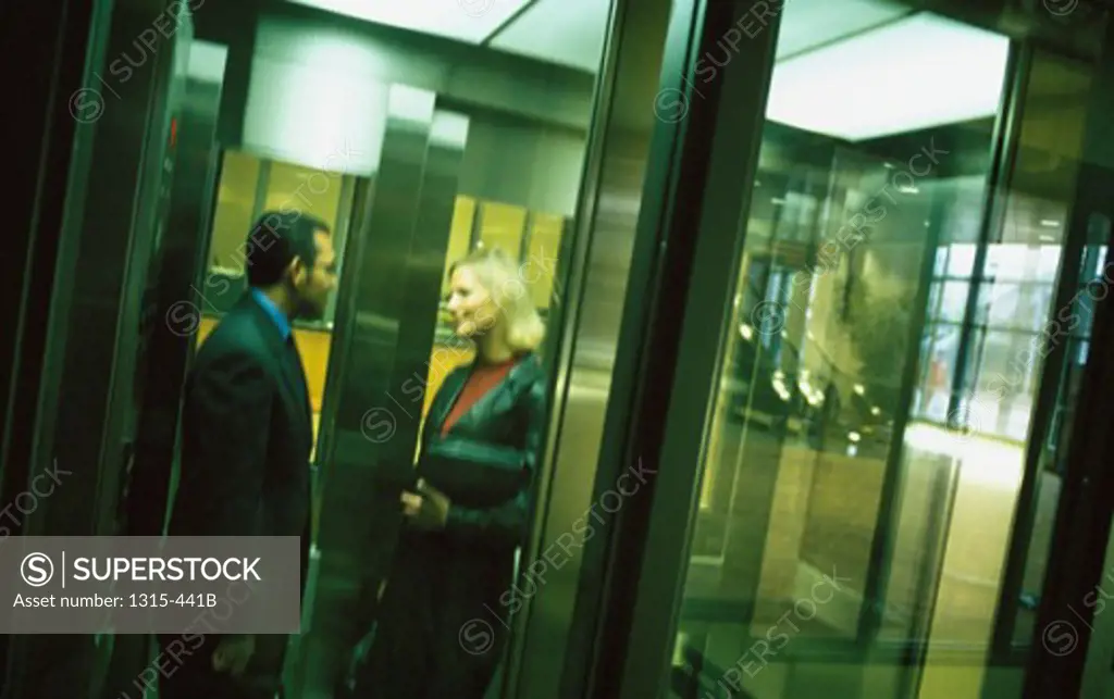 Side profile of a businessman and a businesswoman talking to each other in an elevator