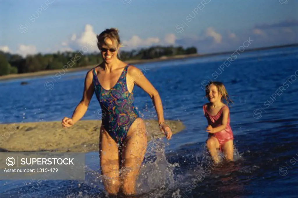 Mother and daughter running in water
