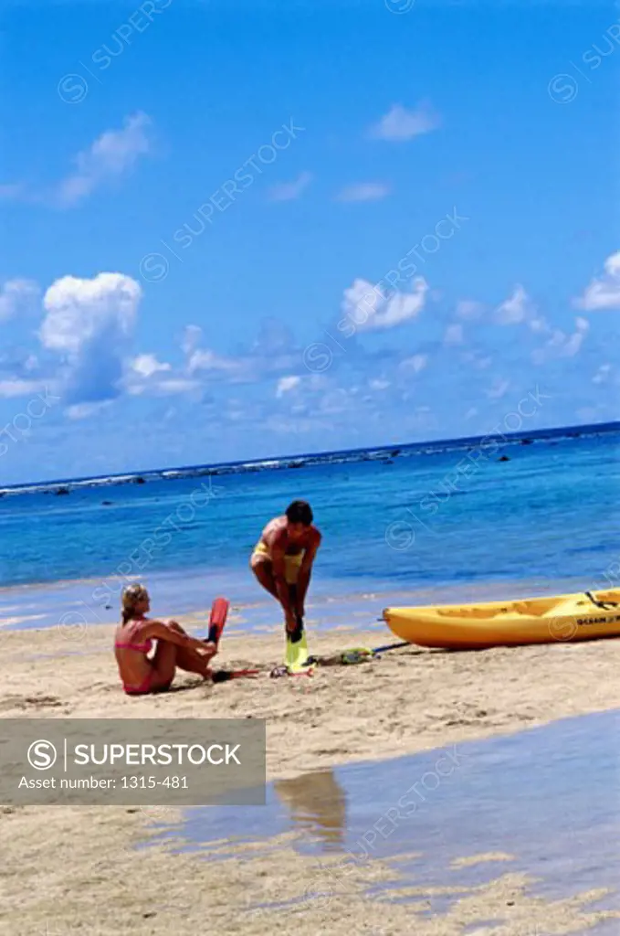 Young couple putting on flippers on the beach