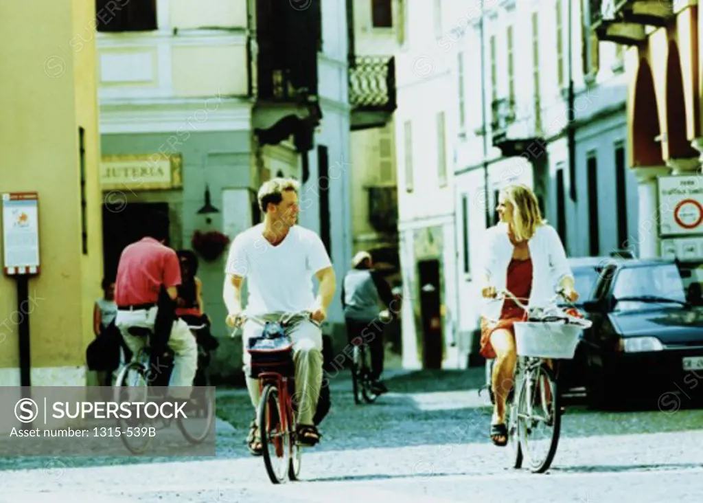 Young couples cycling together on the street, Cremona, Italy