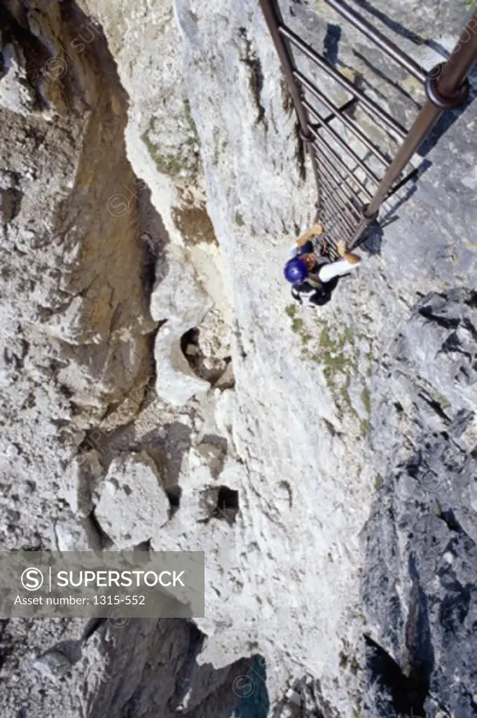 High angle view of a hiker climbing a cliff by ladder