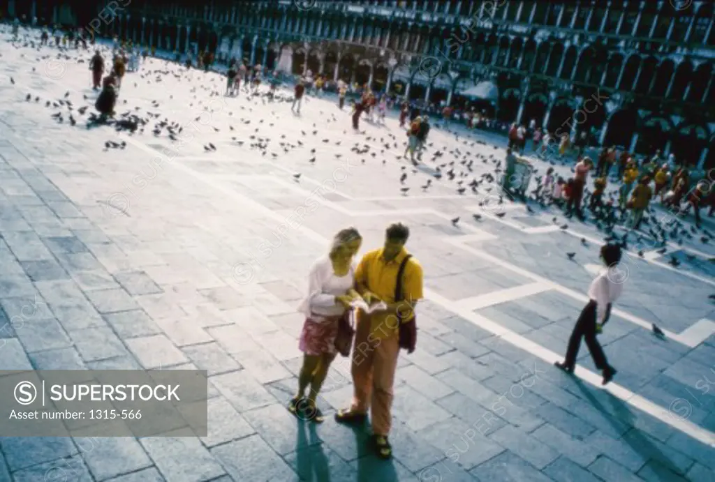 High angle view of a young couple reading a book, Piazza San Marco, Venice, Italy