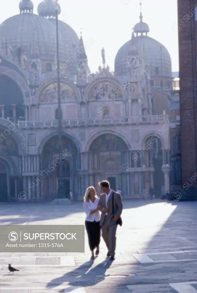 Young couple walking in front of a basilica, Basilica di San Marco, Venice, Italy