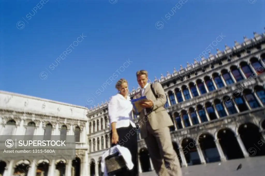 Low angle view of a young couple looking at a map, Piazza San Marco, Venice, Italy