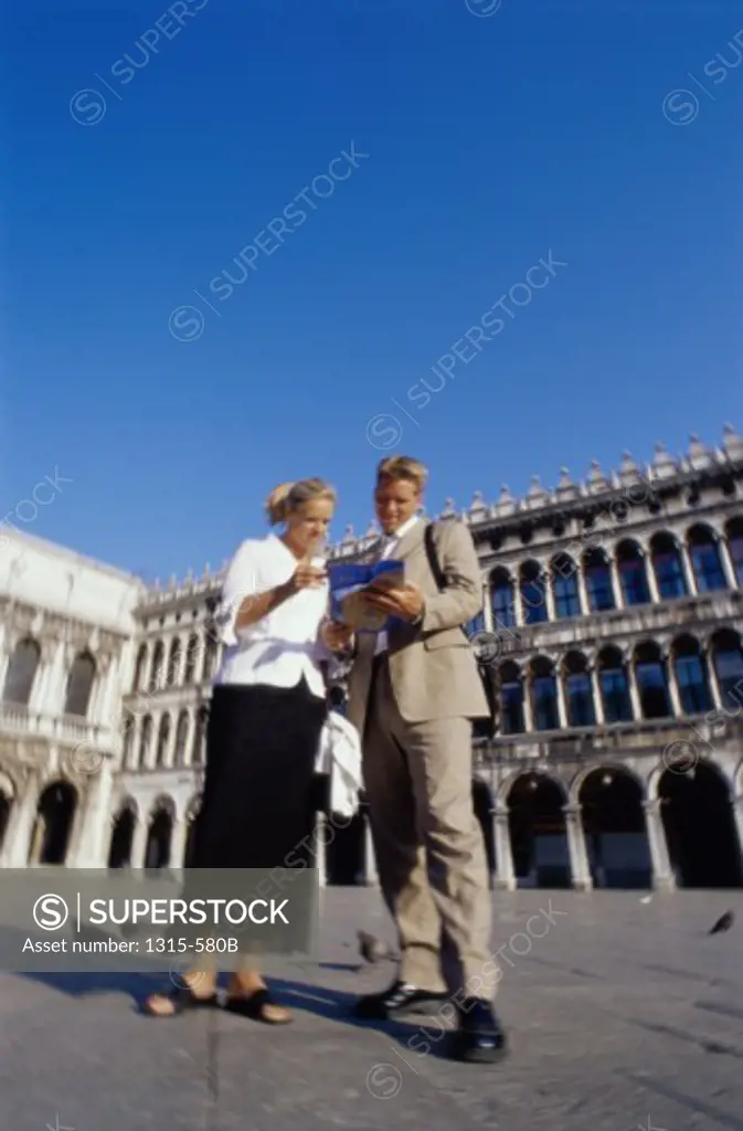 Low angle view of a young couple looking at a map, Piazza San Marco, Venice, Italy