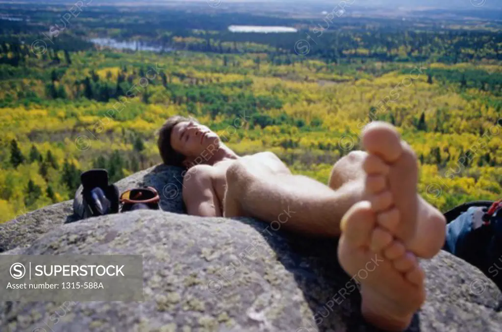 High angle view of a young man sleeping on a rock