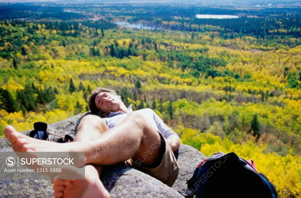 High angle view of a young man sleeping on a rock