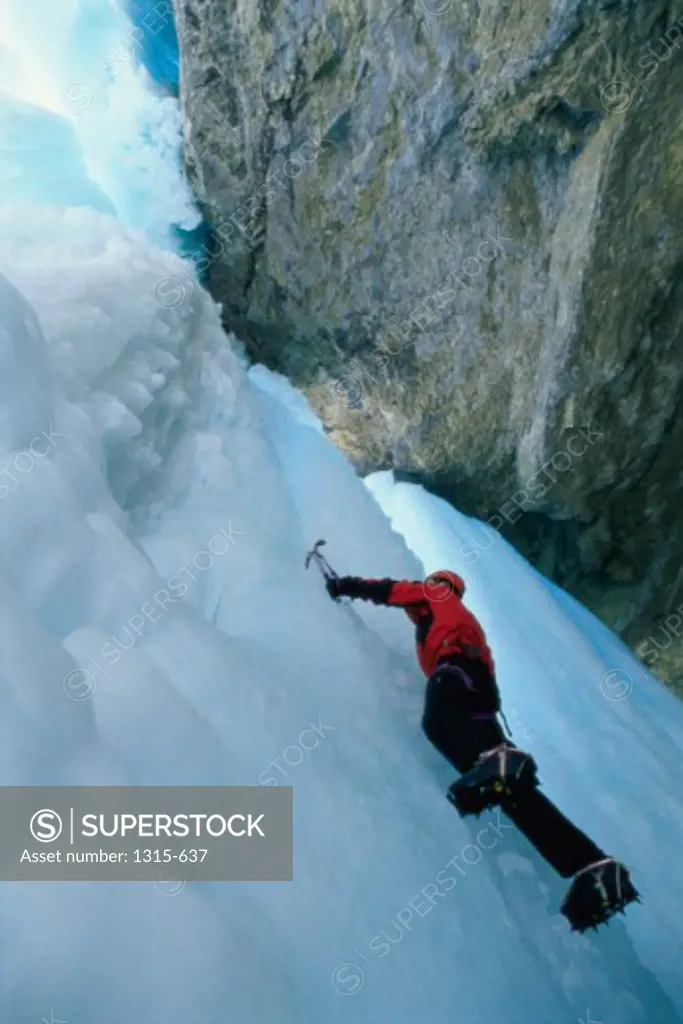 Low angle view of a hiker climbing an ice covered cliff