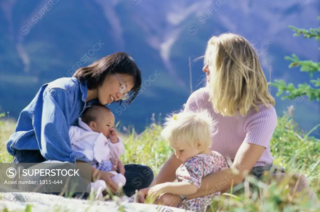 Two mid adult women sitting with their children