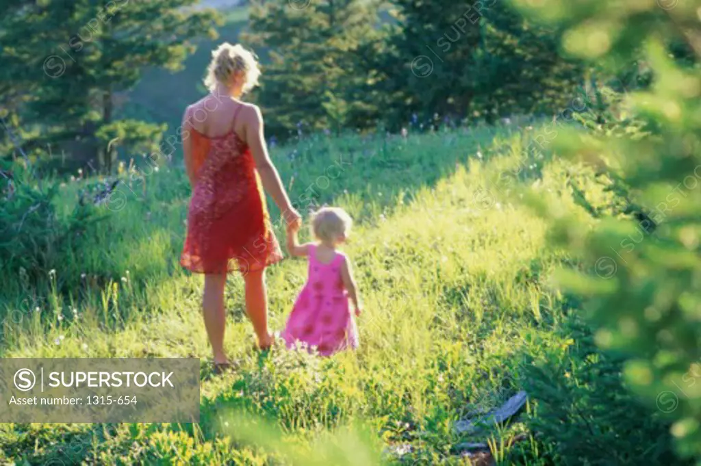 Rear view of a woman walking in the woods with her daughter