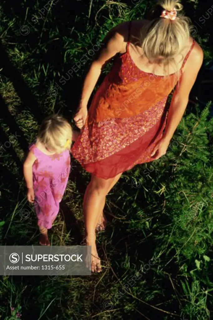 High angle view of a mother and daughter walking on the grass