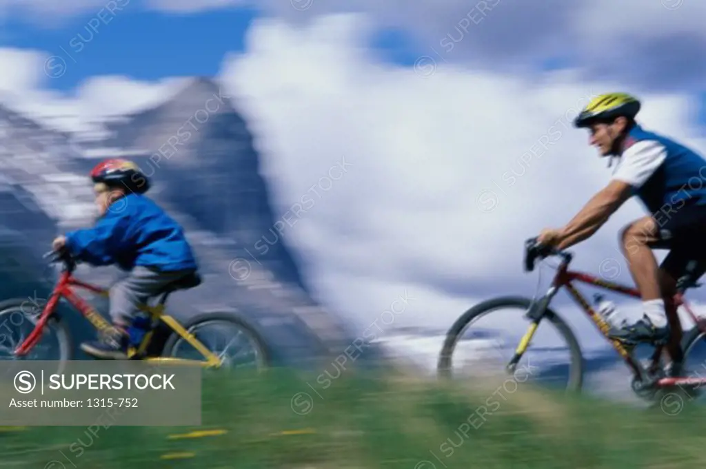 Side profile of a father with son mountain biking, Alberta, Canada