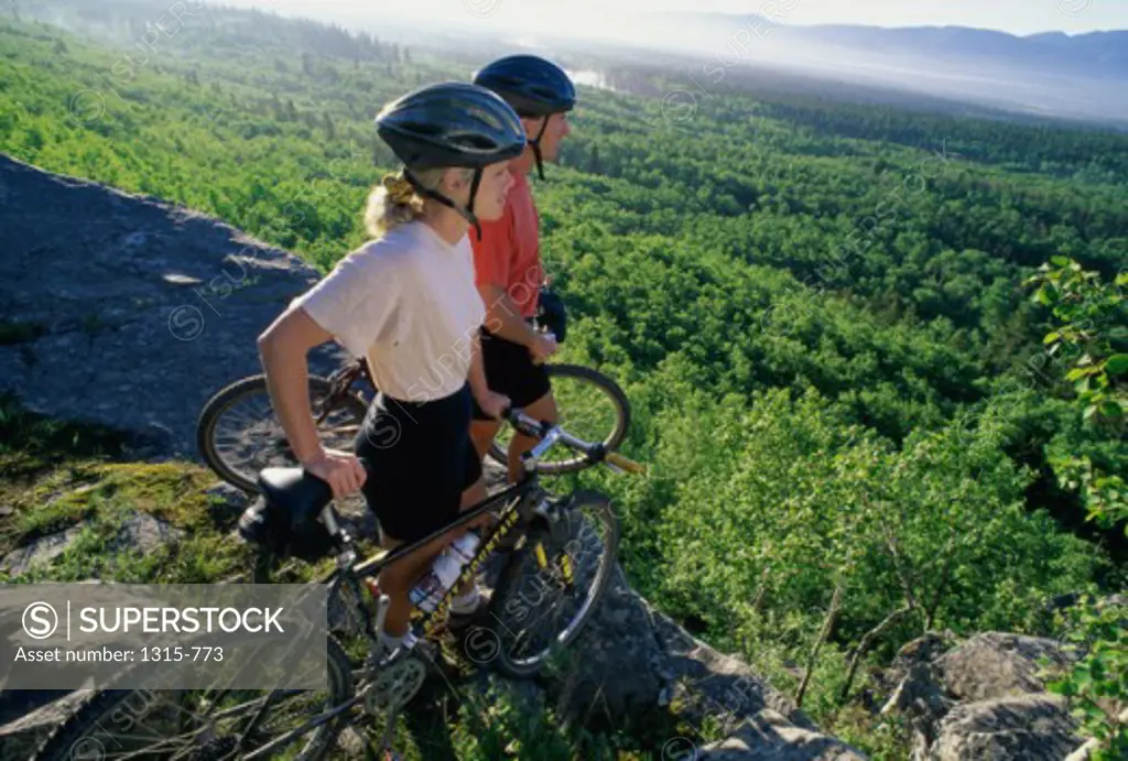 Young couple standing with their bicycles at the edge of a cliff, Banff, Alberta, Canada