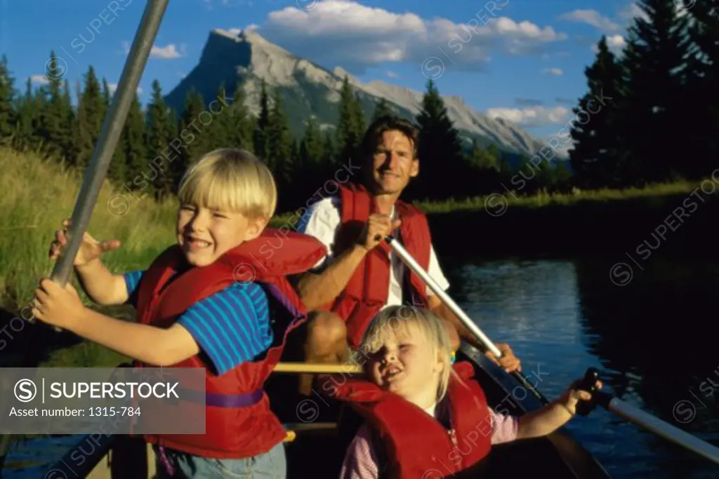 Portrait of a father with his son and daughter boating in a lake, Banff National Park, Alberta, Canada