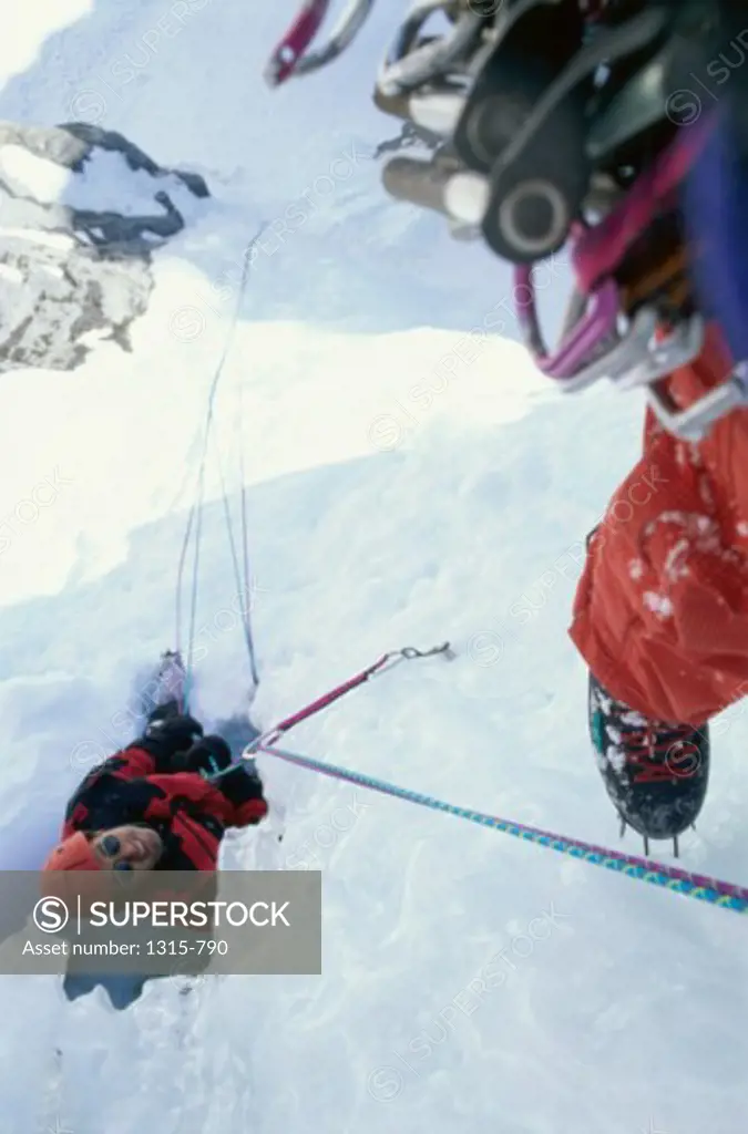 High angle view of two hikers climbing an ice covered cliff