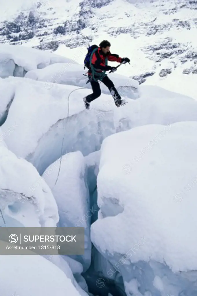 Side profile of a young man leaping across ice covered rocks, Alberta, Canada