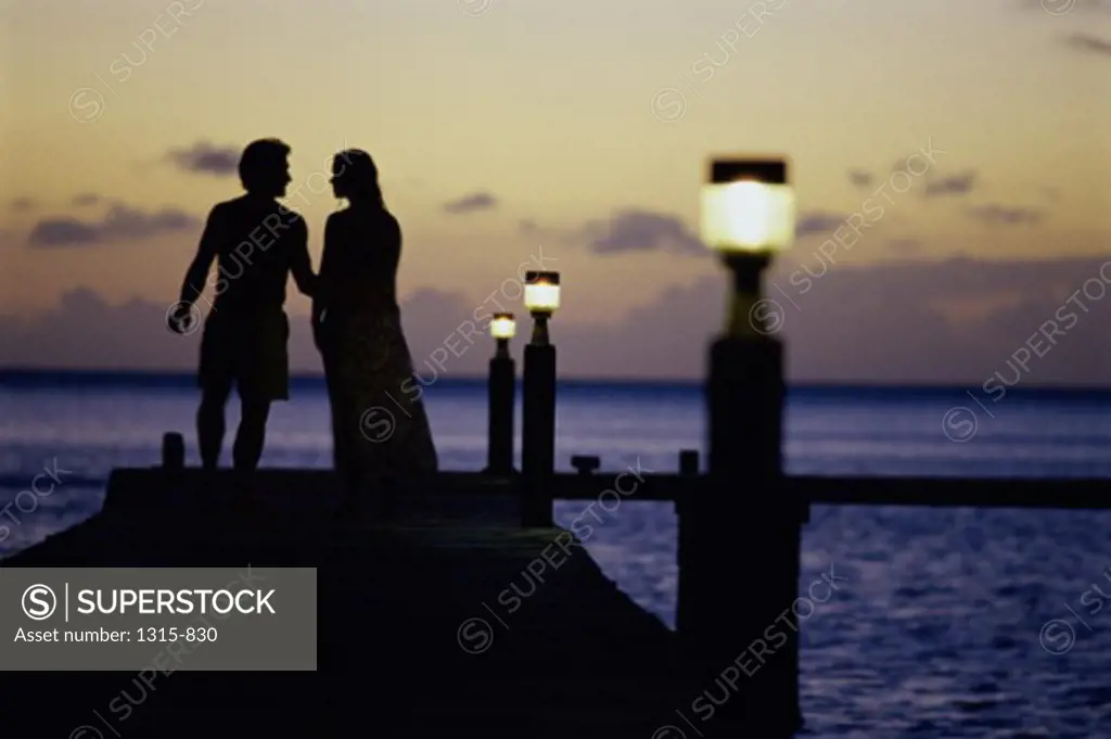 Silhouette of a young couple standing on a boardwalk