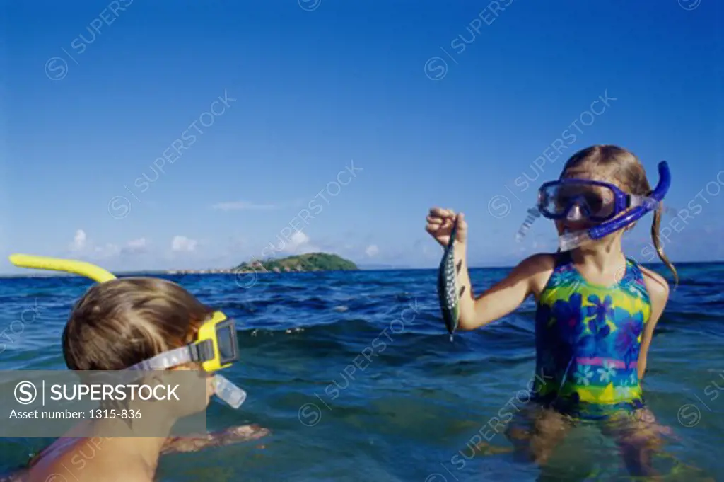 Sister showing a fish to her brother in the sea